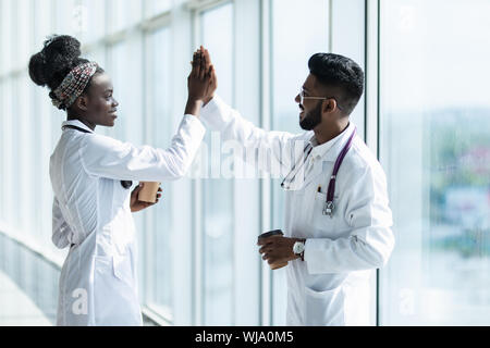 A piena lunghezza shot di un maschio e femmina medico gesticolando alta cinque isolati su sfondo bianco Foto Stock