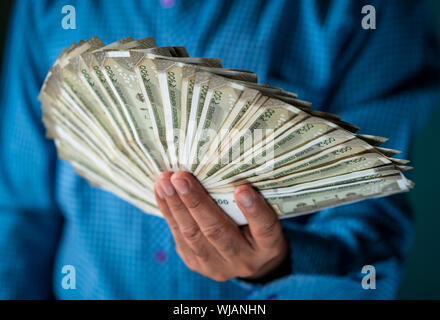 Close up di un maschio di mano che tiene la valuta indiana del cinquecento rupee note. Modello holding concetto di denaro con copyspace. Foto Stock