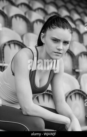 Toni gravi donna seduta su una sedia nello stadio Foto Stock