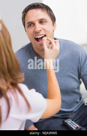 Ritagliate l'alimentazione donna popcorn per un uomo felice a casa Foto Stock