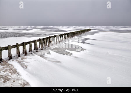 Vecchio molo in legno sul lago Ijsselmeer congelati in inverno, Paesi Bassi Foto Stock