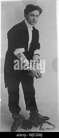 Harry Houdini, ritratto a figura intera, in piedi, rivolto verso destra in catene Foto Stock