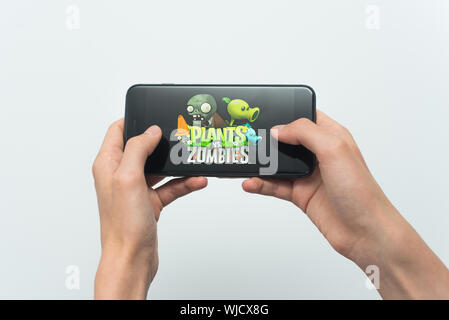 Samara, Russia -07, 29, 2019: un giovane ragazzo svolge un Plants vs. Zombies gioco su Iphone 8 Plus. Ragazzo adolescente in possesso di un telefono cellulare nelle sue mani con un gioco piante vs Zombies mobile su uno sfondo bianco. Foto Stock