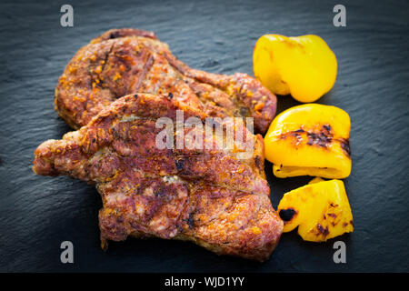 Carne, bistecche con verdure alla griglia su sfondo scuro. Foto Stock