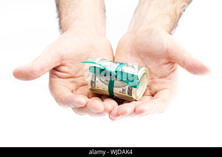 Di dollari arrotolato in un tubo legate con nastro in mani Foto Stock