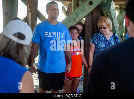 Gruppo di Chiesa pregando per un uragano di mancare la isola di palme, S.C. Il gruppo sta pregando sotto il molo sul isola di palme. Foto Stock