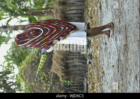 DUGUM DANI VILLAGE, Il Baliem Valley, Irian Jaya, Nuova Guinea, Indonesia - Juny 20, 2012: Dani donna in un moderno abito bianco e la PAC tradizionale su un hea Foto Stock