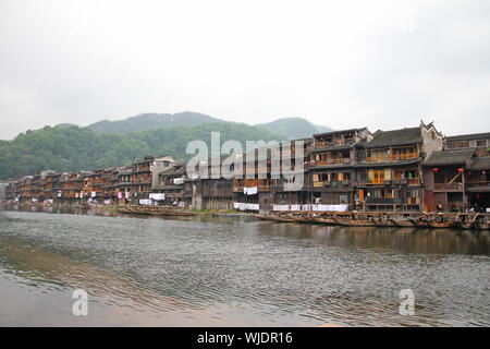 FENGHUANG - 12 Maggio: imbarcazione in legno e case in legno al fiume tuojiang in fenghuang antica città il 12 maggio 2011 di Fenghuang, Cina. Foto Stock