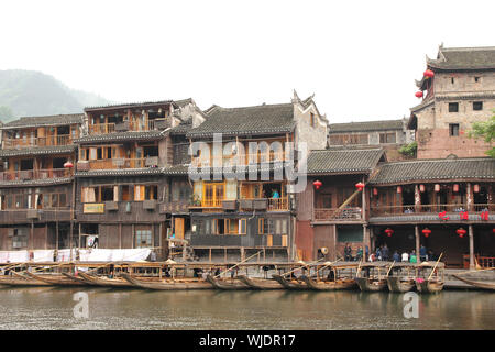 FENGHUANG - 12 Maggio: imbarcazione in legno e case in legno al fiume tuojiang in fenghuang antica città il 12 maggio 2011 di Fenghuang, Cina. Foto Stock