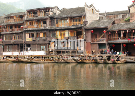 FENGHUANG - 12 Maggio: imbarcazione in legno e case in legno al fiume tuojiang in fenghuang antica città il 12 maggio 2011 di Fenghuang, Cina. Foto Stock