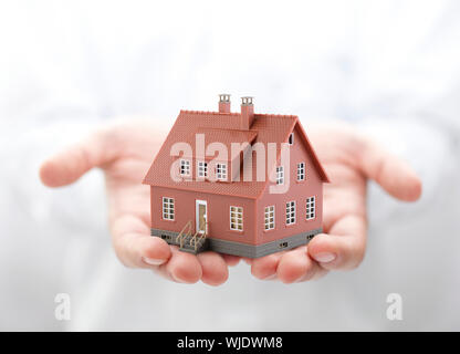 Casa marrone miniatura in mani Foto Stock