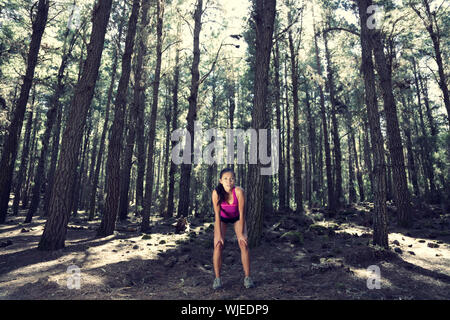 Runner rilassante dopo aver eseguito nel suggestivo bosco incantato. Bella donna modello. Foto Stock