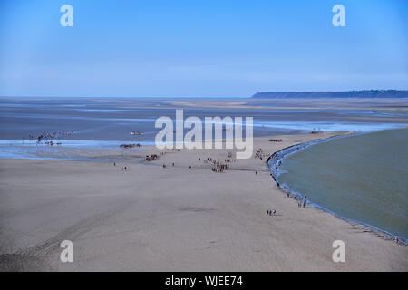 Pellegrini camminando di fronte al Mont Saint Michel durante la bassa marea. Foto Stock