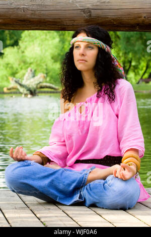 Fotografia di una bella donna hippie meditando sul fiume beach Foto Stock