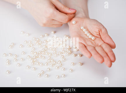 Mani femminili una raccolta di perle da perle di grandi dimensioni Foto Stock