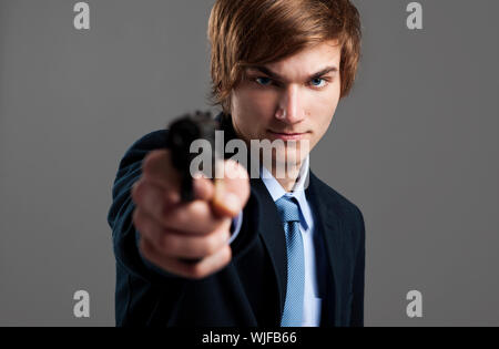 Sottolineato businessman holding e indicando una pistola per la fotocamera Foto Stock