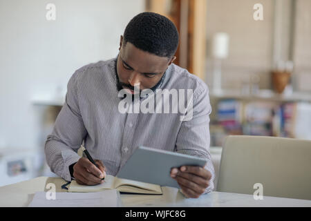 Giovane americano africano uomo utilizzando una tavoletta digitale in casa Foto Stock