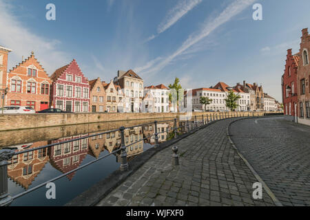 Bella e antica a due piani di case con la riflessione in un canale di Bruges e di una strada di ciottoli, a Bruges, Belgio Foto Stock