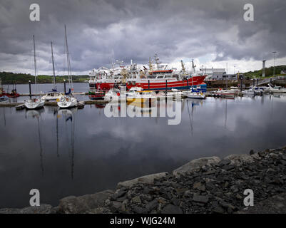 Killybegs, Co. Donegal, Irlanda - 19 Maggio 2019 - porto di yacht, navi da pesca, coperto il cielo e la banchina di pietra in primo piano. Foto Stock