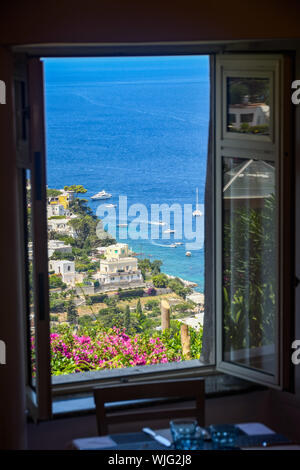 Isola di Capri - Agosto 2019: vista panoramica della costa dell'isola di Capri è incorniciato dalla finestra aperta di un ristorante nella città di Capri. Foto Stock