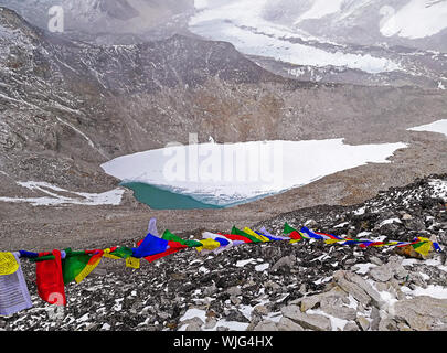 Buddista Tibetana preghiera multicolori bandiere svolazzanti nel vento sullo sfondo di frozen il Lago Moraine, campo base Everest e ghiacciai Himalaya in Ne Foto Stock