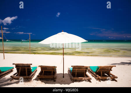 Sedie a sdraio e ombrelloni sulla spiaggia di sabbia bianca di fronte alla laguna Foto Stock