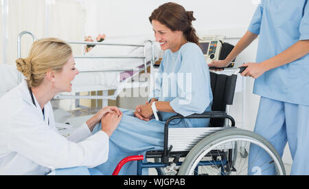 Vista laterale di un medico parlando a un paziente di sesso femminile in sedia a rotelle in ospedale Foto Stock