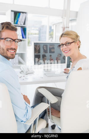 Vista posteriore del ritratto di fotografia lavorando sul computer in un ufficio luminoso Foto Stock