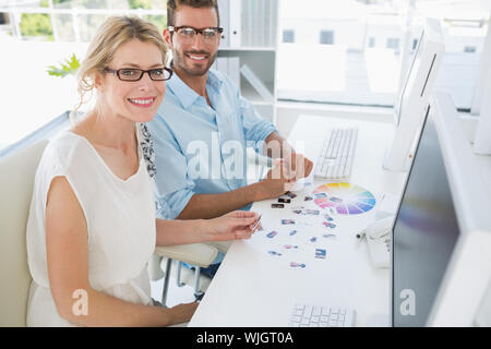 Vista laterale ritratto di fotografia lavorando sul computer in un ufficio luminoso Foto Stock