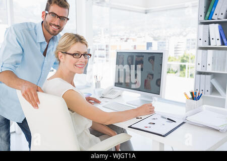 Vista laterale ritratto di fotografia lavorando sul computer in un ufficio luminoso Foto Stock