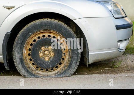 Auto con pneumatico sgonfio sul vecchio cerchione arrugginito Foto Stock