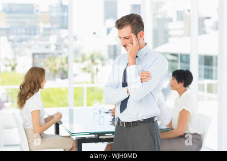 Considerato imprenditore con i colleghi nella riunione dietro a un ufficio luminoso Foto Stock