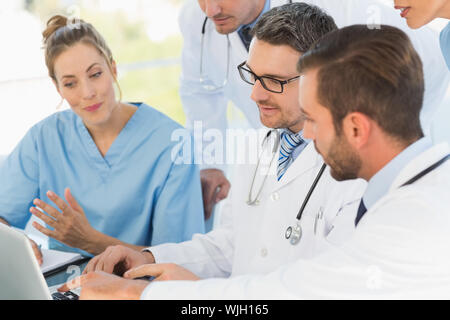 Il gruppo di medici concentrato utilizzando laptop insieme all'ufficio medico Foto Stock