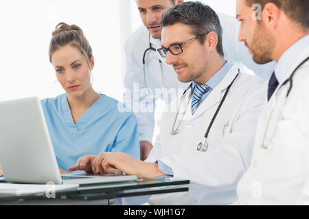 Il gruppo di medici concentrato utilizzando laptop insieme all'ufficio medico Foto Stock