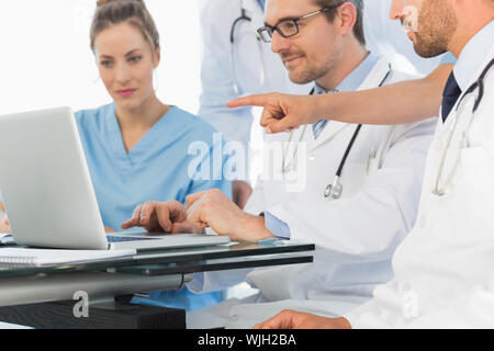 Il gruppo di medici concentrato utilizzando laptop insieme all'ufficio medico Foto Stock