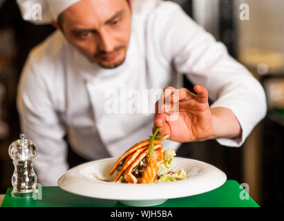 Chef di aggiungere il tocco finale al delizioso salmone al forno Foto Stock