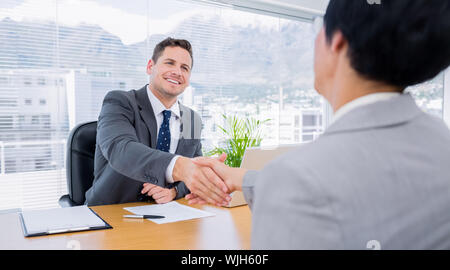 Elegantemente vestito dirigenti stringono le mani dopo una riunione di lavoro in ufficio Foto Stock
