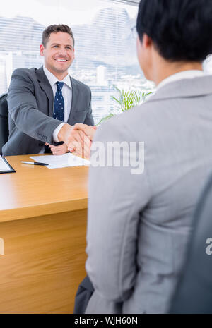 Elegantemente vestito dirigenti stringono le mani dopo una riunione di lavoro in ufficio Foto Stock