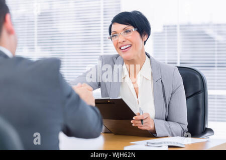 Elegantemente vestito dirigenti stringono le mani dopo una riunione di lavoro in ufficio Foto Stock