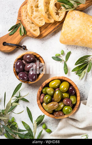 Olive, ciabatta e olio di oliva su sfondo bianco. Foto Stock