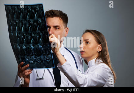 I medici team con MRI scan spinale ritratto contro uno sfondo grigio Foto Stock