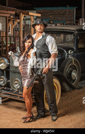 Bello muscoloso 1920s i gangster con lady in mini gonna Foto Stock
