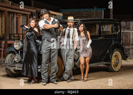 Gruppo misto di 1920s vintage gangster al di fuori Foto Stock