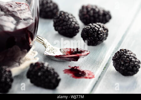 Cucchiaio disordinato con gelatina di blackberry su un tavolo blu. Estrema profondità di campo e la messa a fuoco selettiva su jelly sul cucchiaio. Foto Stock