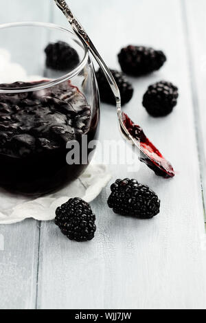 Cucchiaio disordinato con blackberry conserva su un tavolo blu. Estrema profondità di campo. Foto Stock