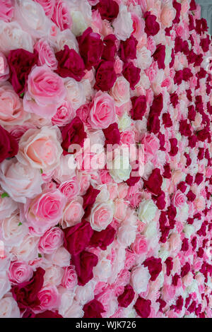Parete di bianco, rosa e rose rosse a una festa di battesimo Foto Stock