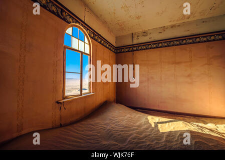 Stanza vuota con una finestra e la sabbia in le rovine di una città fantasma Kolmanskop, Namibia Foto Stock