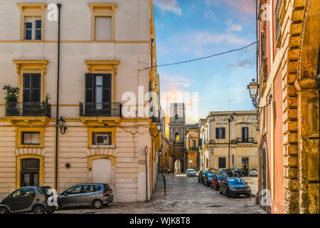 Un giovane è visto in lontananza come essi vicino a una chiesa medievale torre nello storico quartiere residenziale di Brindisi, Italia. Foto Stock