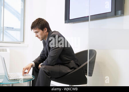 Vista laterale di un imprenditore stanco utilizzando laptop in sala di attesa Foto Stock