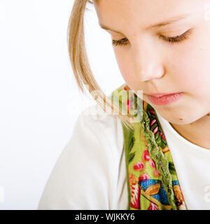 Studio colpo alla testa di una splendida bionda bambina in camicia bianca e abito verde cercando sognanti Foto Stock